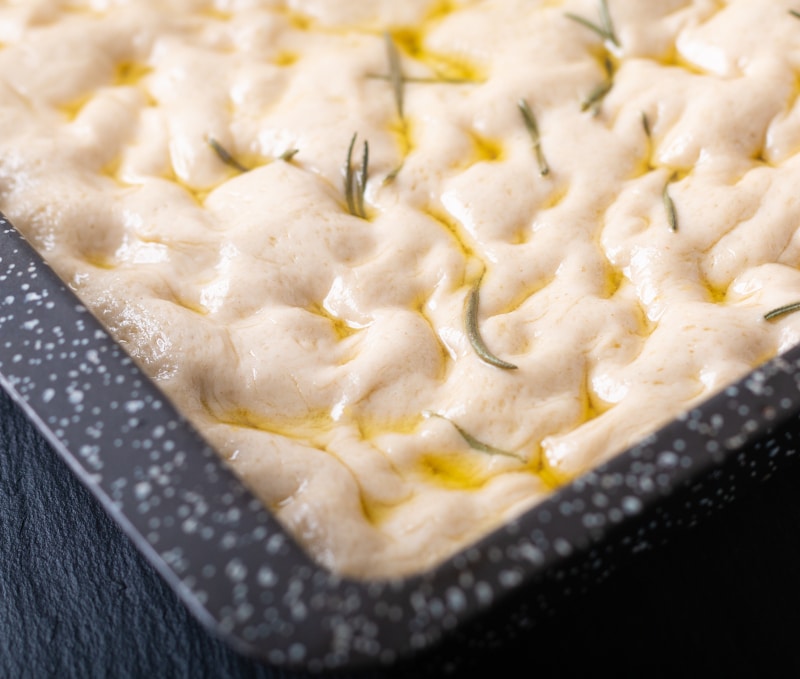 Food concept homemade organic focaccia dough in iron pan with copy space